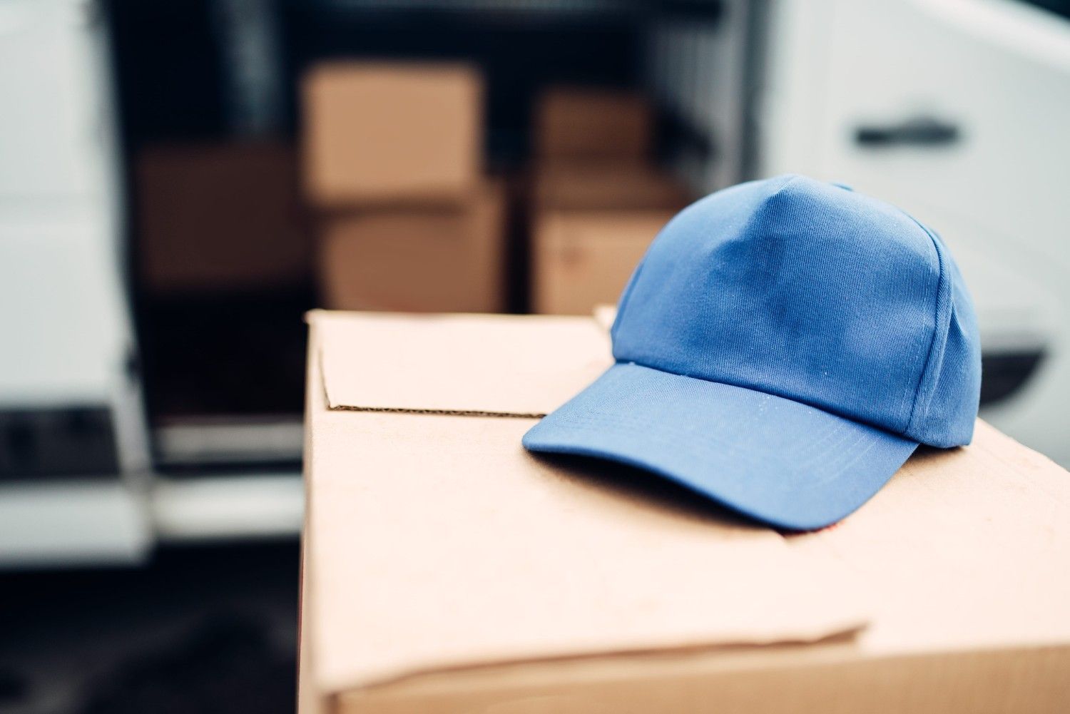 Gorra azul apoyada sobre una caja de cartón en un entorno de almacén.