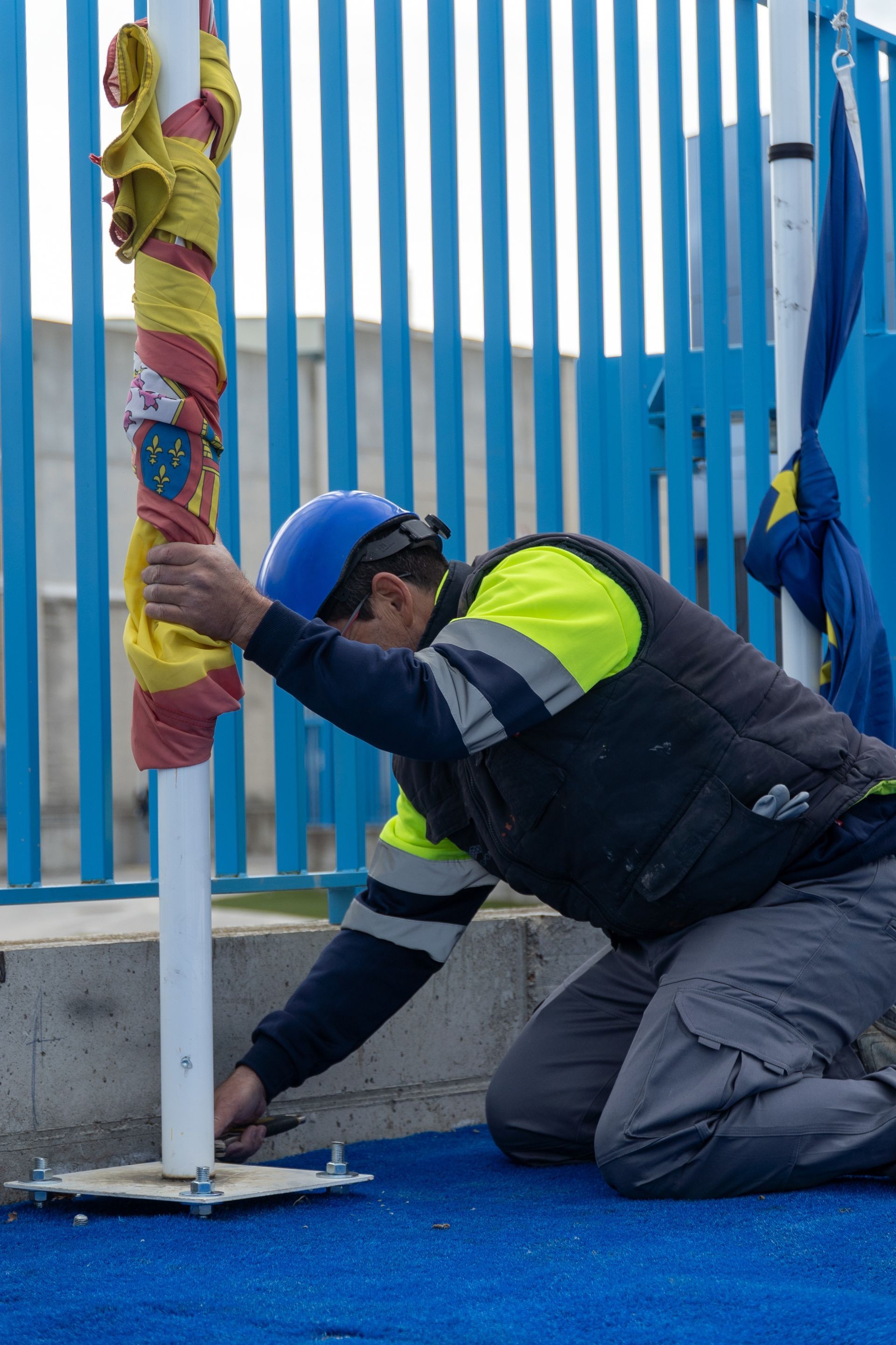 Un hombre que lleva un casco está trabajando en un asta de bandera.