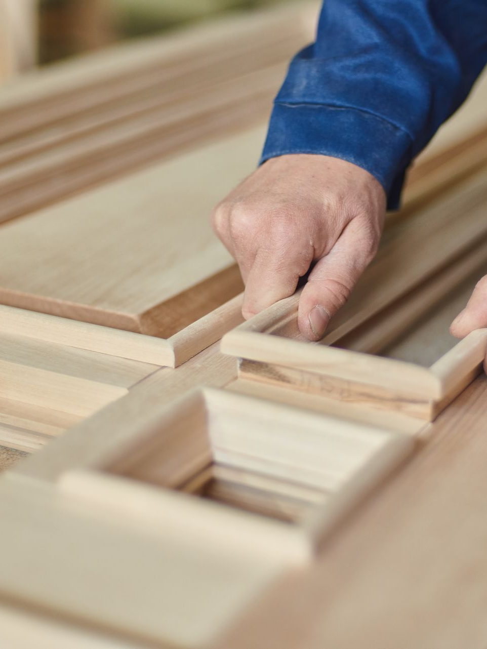 Mains d'une personne assemblant un cadre en bois avec précision ; environnement d'atelier intérieur.