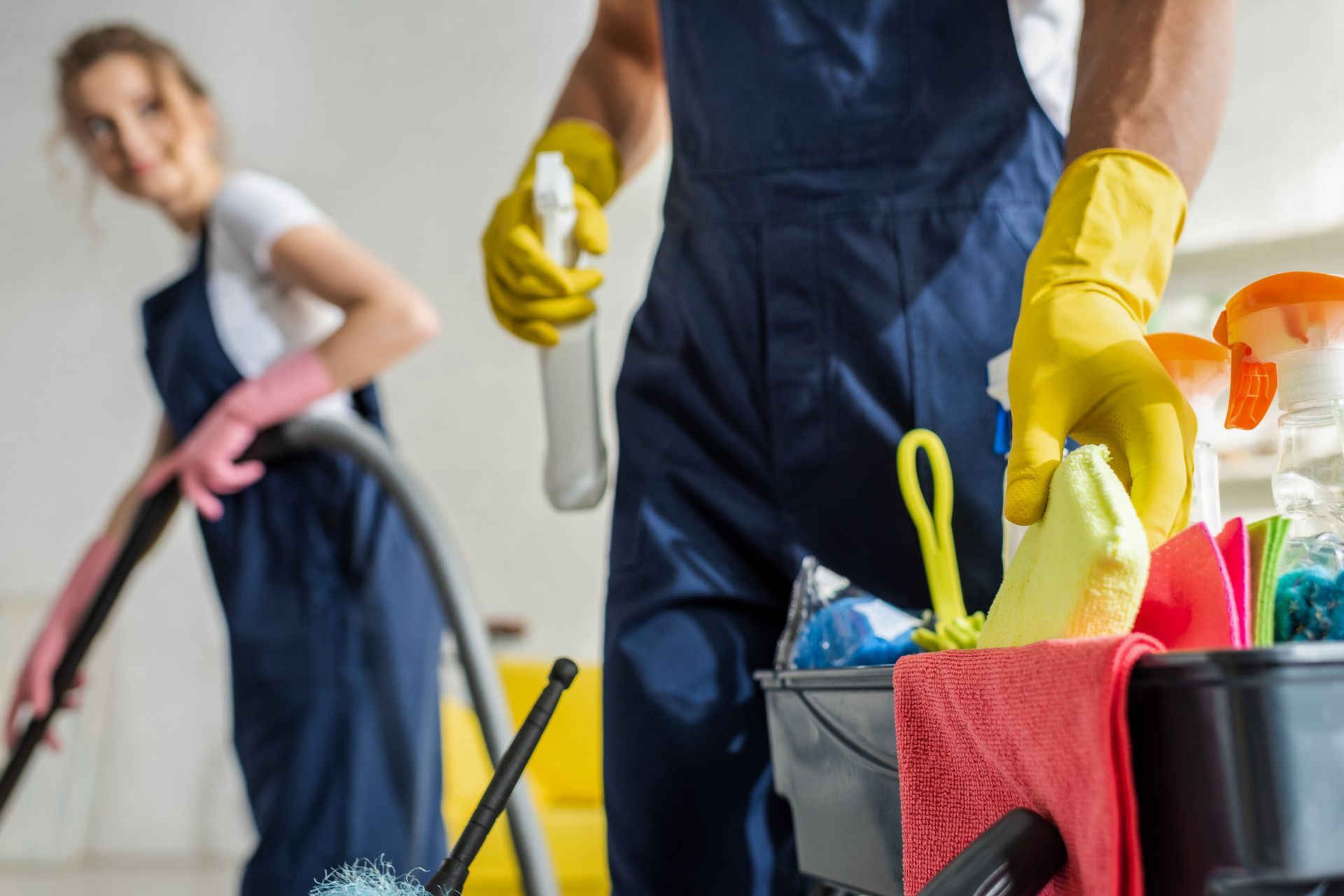 Un hombre y una mujer están limpiando una habitación con productos de limpieza.