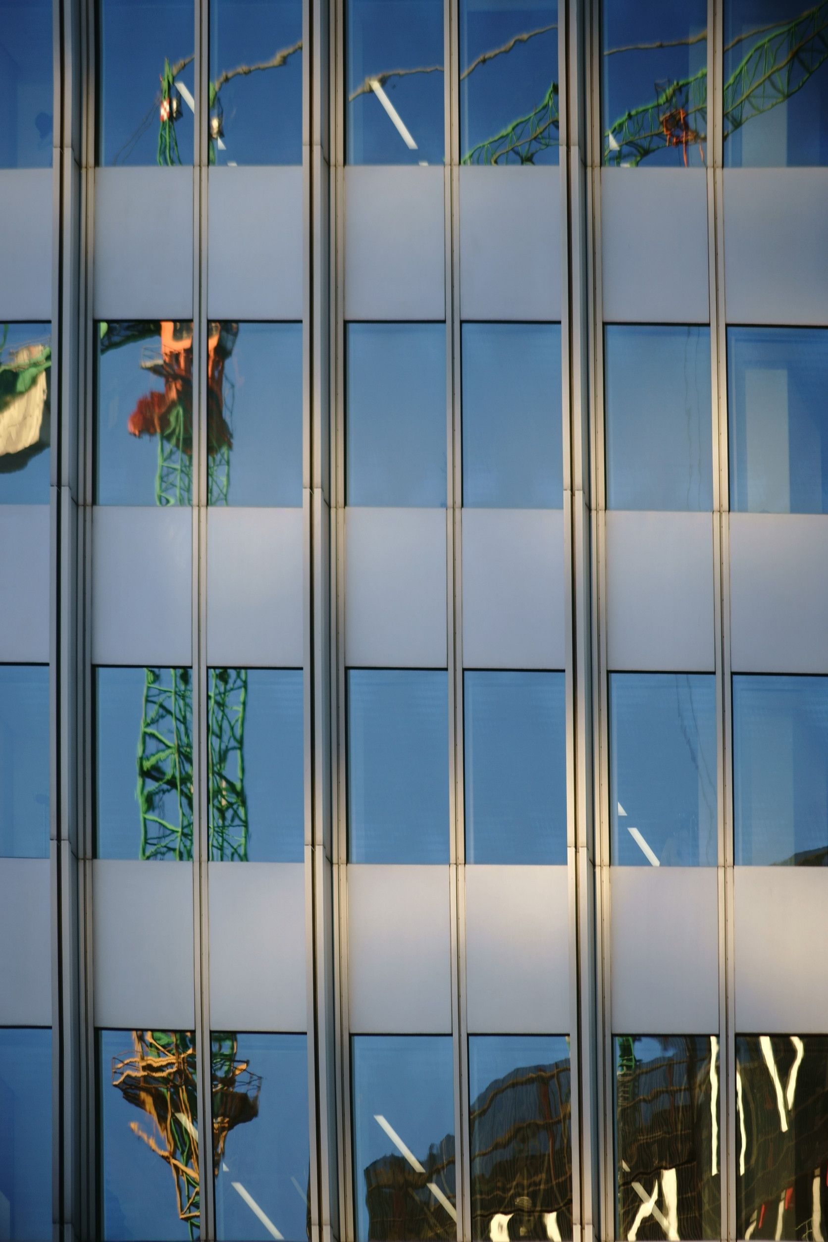 Un edificio con el reflejo de una grúa en las ventanas.