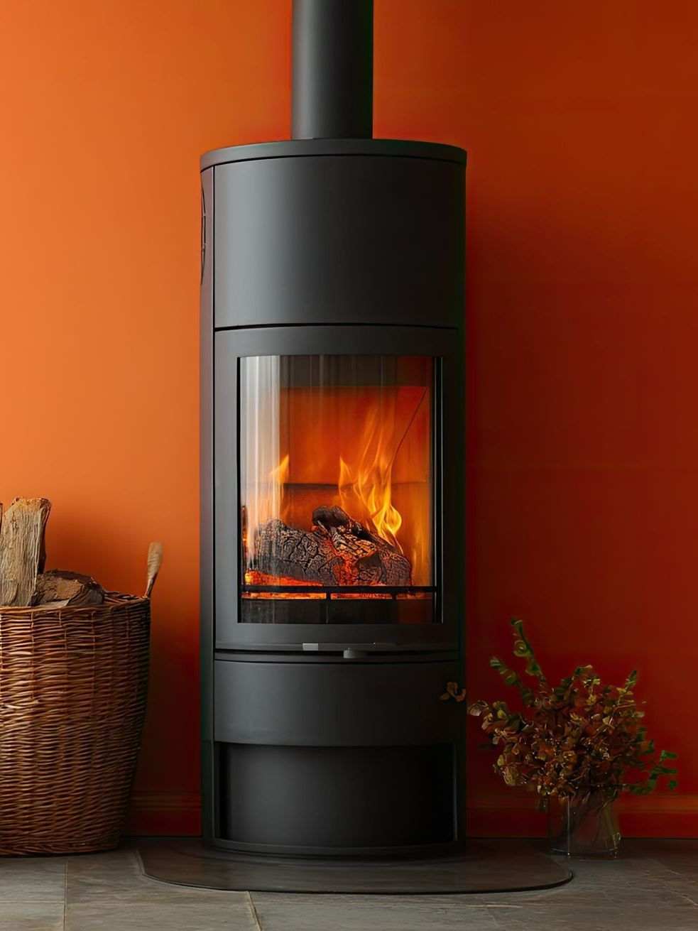 Poêle à bois allumé devant un mur orange