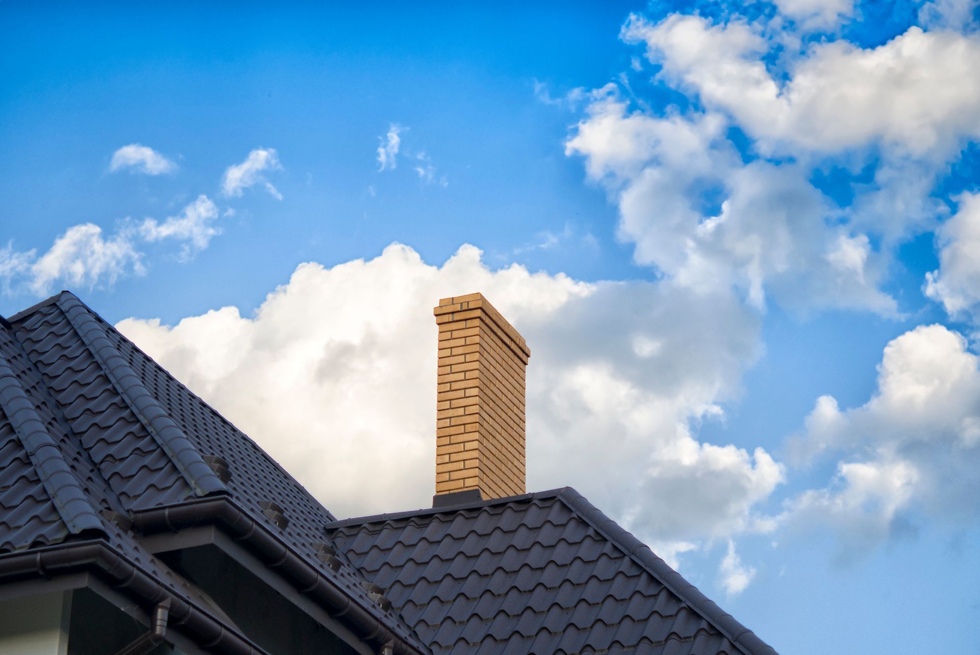 Cheminé beige sur un toit noir avec un ciel bleu en fond