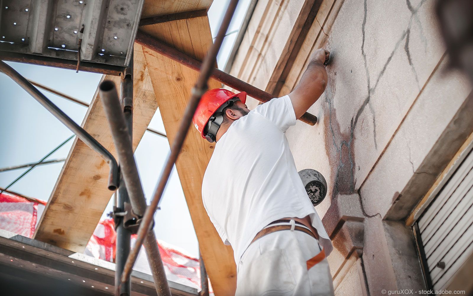 Ein professioneller Handwerker führt präzise Malerarbeiten an einer Wand durch.