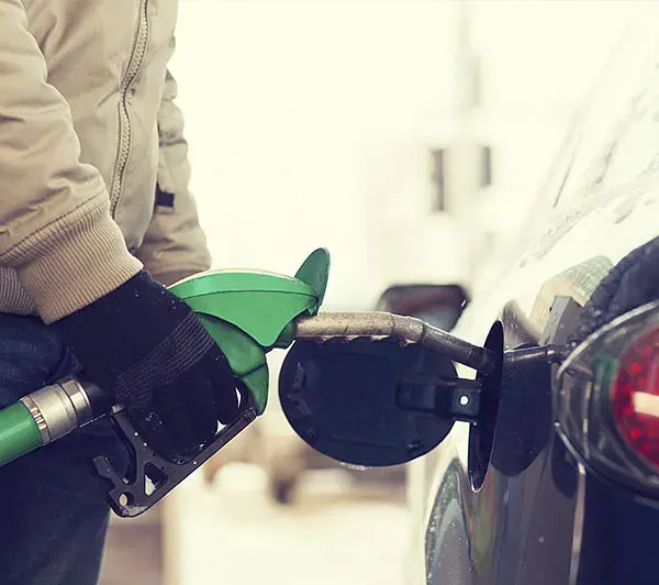 Un hombre está echando gasolina a un coche en una gasolinera.