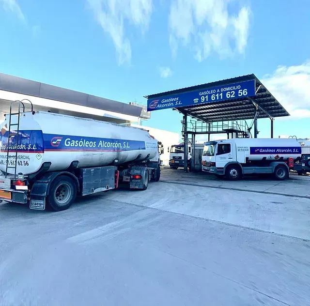 Dos camiones cisterna están estacionados frente a una gasolinera.