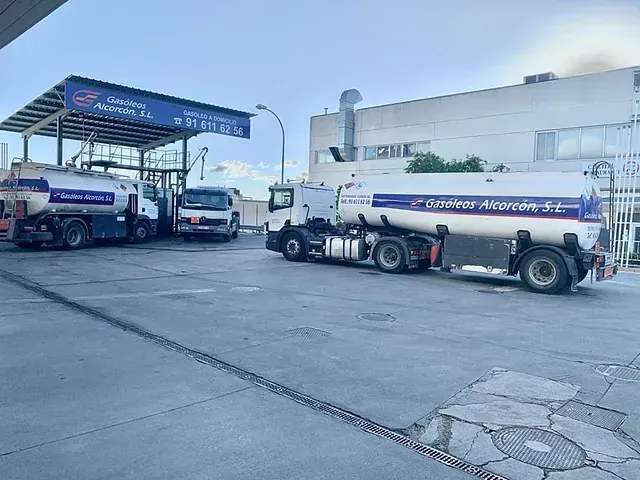 Un camión cisterna está estacionado frente a un edificio en una gasolinera.