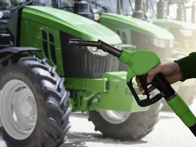 Una persona está cargando gasolina en un tractor verde.