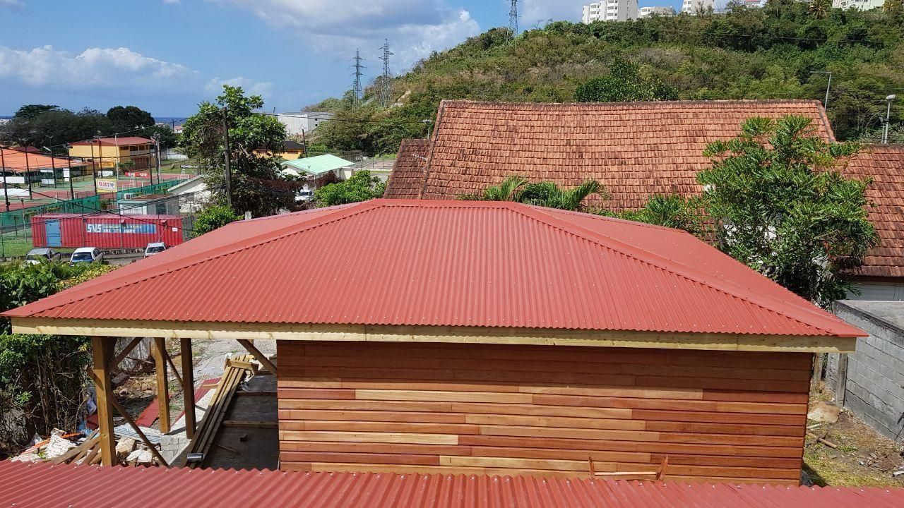 Toiture en tôle ondulée rouge sur une structure en bois.