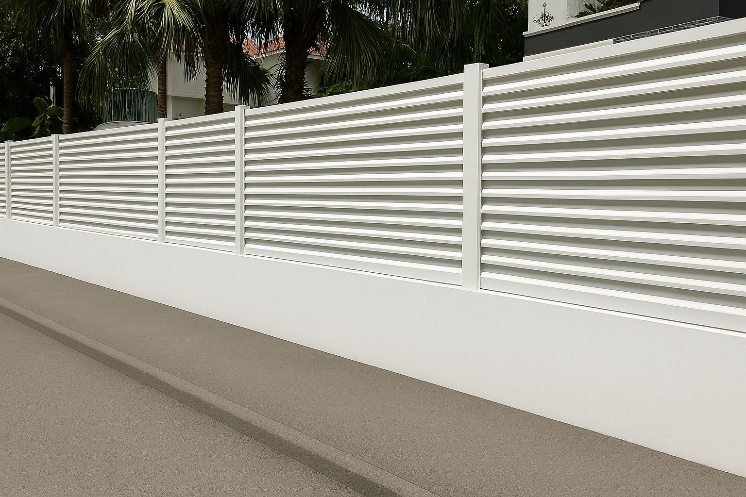 Une clôture blanche moderne à lattes horizontales reposant sur une base en béton blanc massif, jouxtant un trottoir pavé gris.