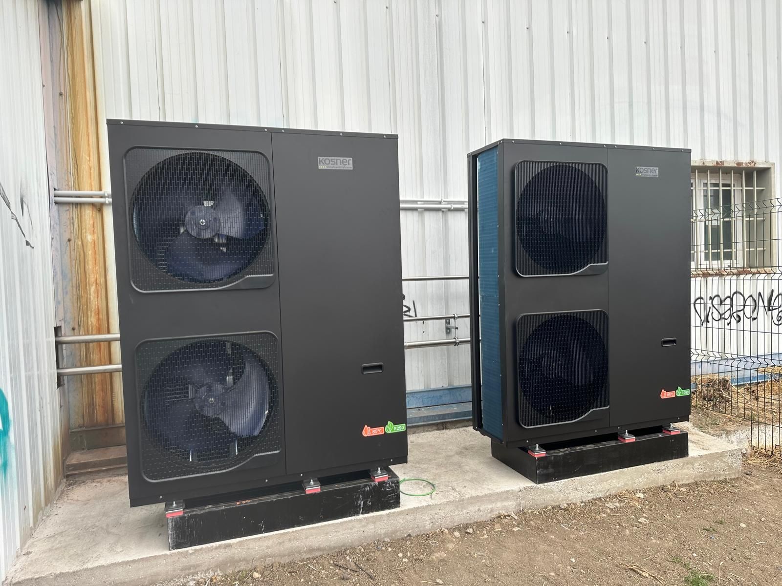 Dos bombas de calor exteriores negras sobre una losa de hormigón.