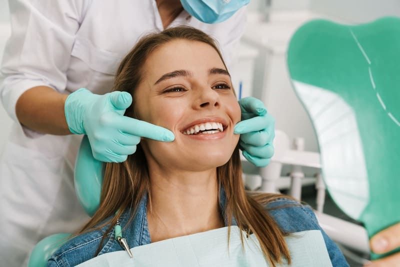Eine Frau sitzt auf einem Zahnarztstuhl, während ein Zahnarzt ihre Zähne untersucht | Zahnmedizin am Neckar