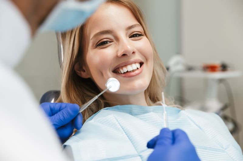 Eine Frau sitzt auf einem Zahnarztstuhl, während ein Zahnarzt ihre Zähne untersucht | Zahnmedizin am Neckar