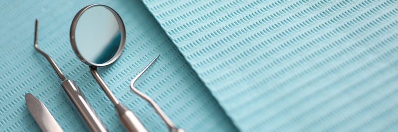 Ein zahnärztlicher Spiegel, zahnärztliche Instrumente und ein zahnmedizinisches Handtuch auf einem Tisch | Zahnmedizin am Neckar