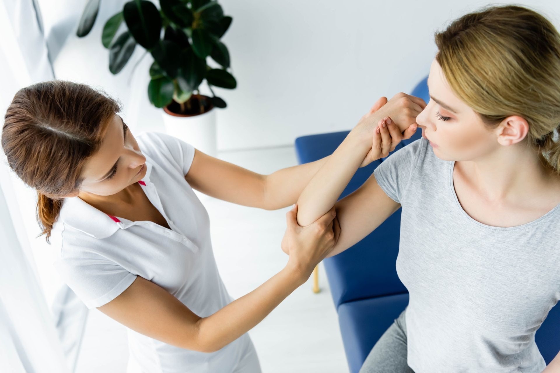 A una mujer le examina el codo un médico.