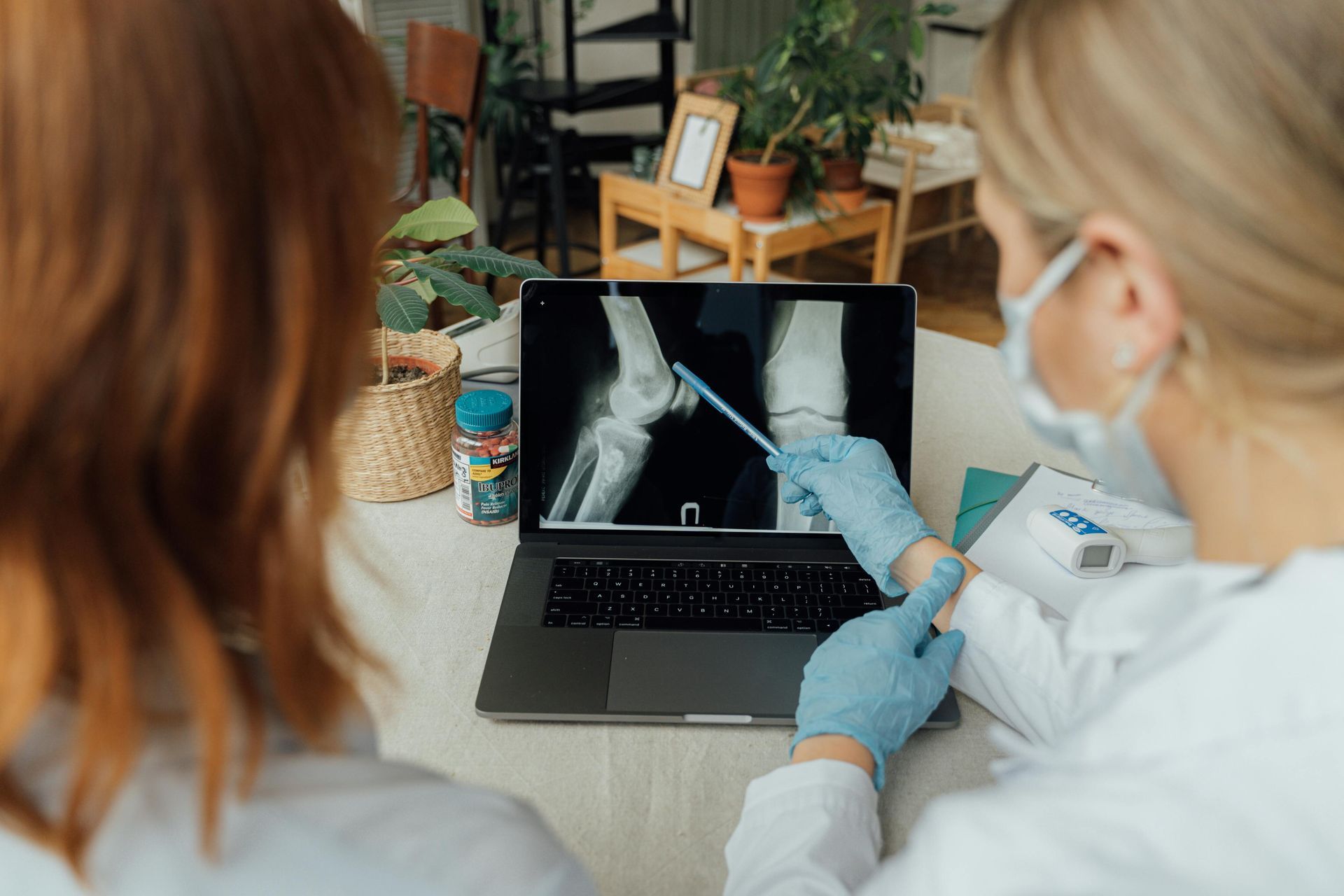 Dos médicos están mirando una radiografía de una rodilla en una computadora portátil.