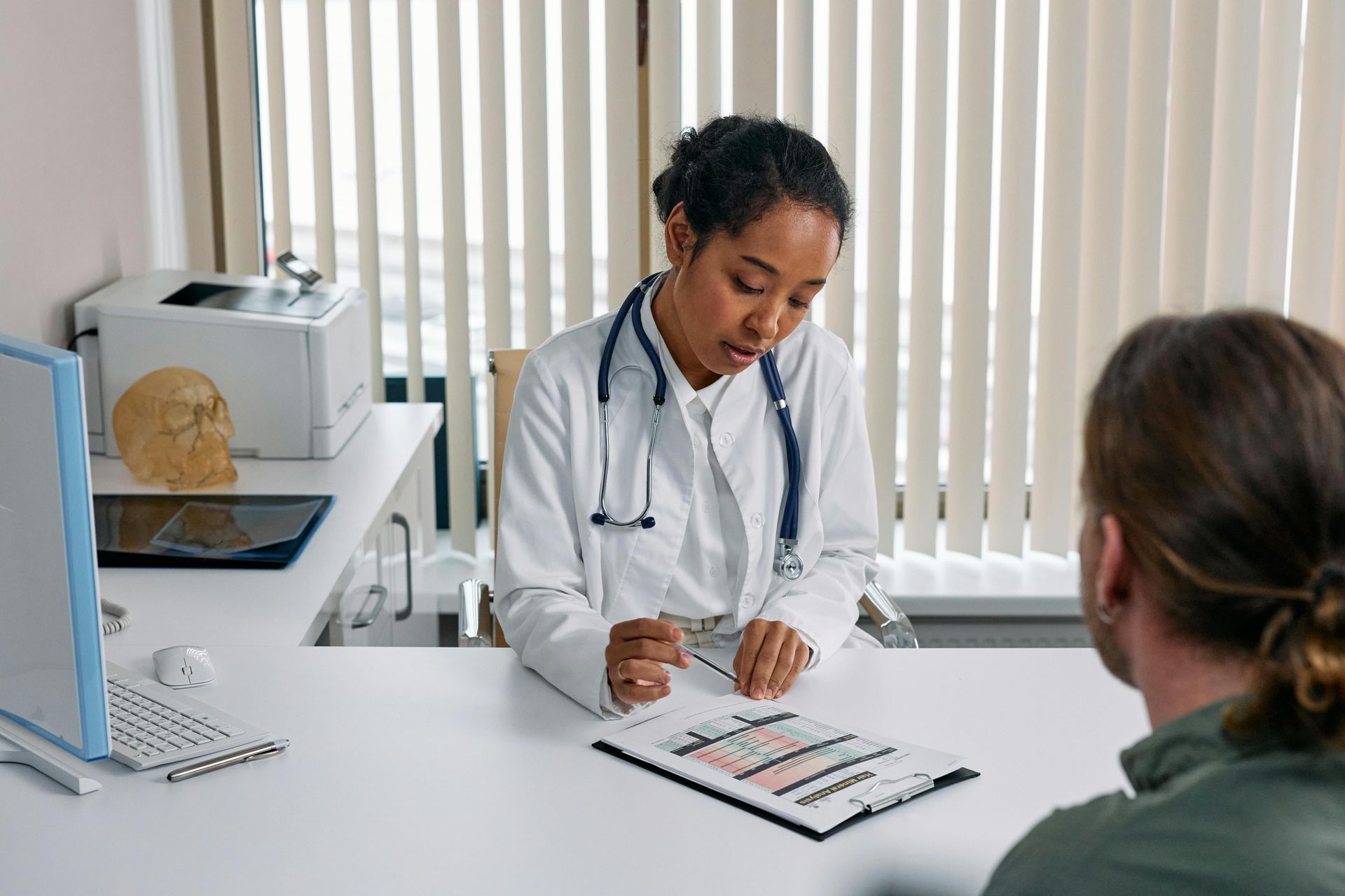 Un médico está sentado en un escritorio hablando con un paciente.
