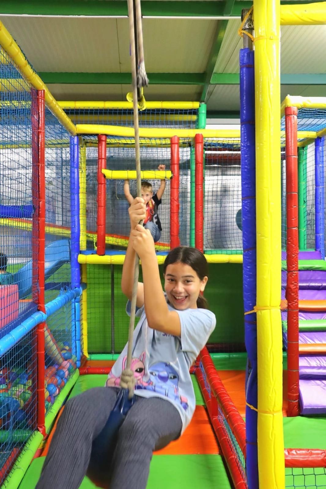 Parque infantil interior con piscina de pelotas de colores, estructuras para escalar y túneles.