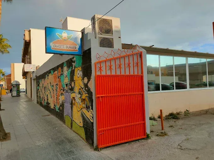 Exterior del restaurante con puerta naranja, mural y cartel que dice "Smarts Burger".