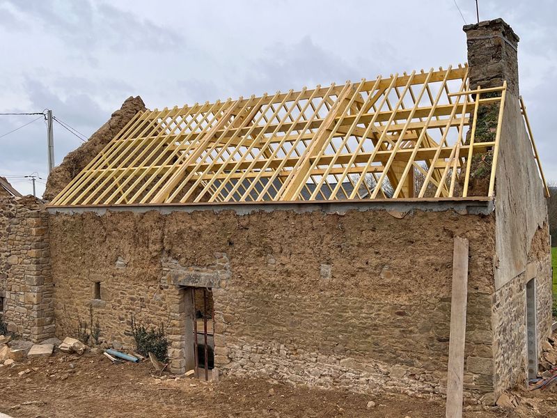 Maison en pierre en cours de rénovation, avec une nouvelle charpente en bois et une cheminée à droite