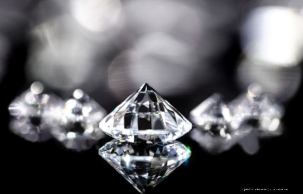 Diamanten auf einer reflektierenden schwarzen Oberfläche, scharf fokussiert. Verschwommener Hintergrund mit anderen Diamanten.