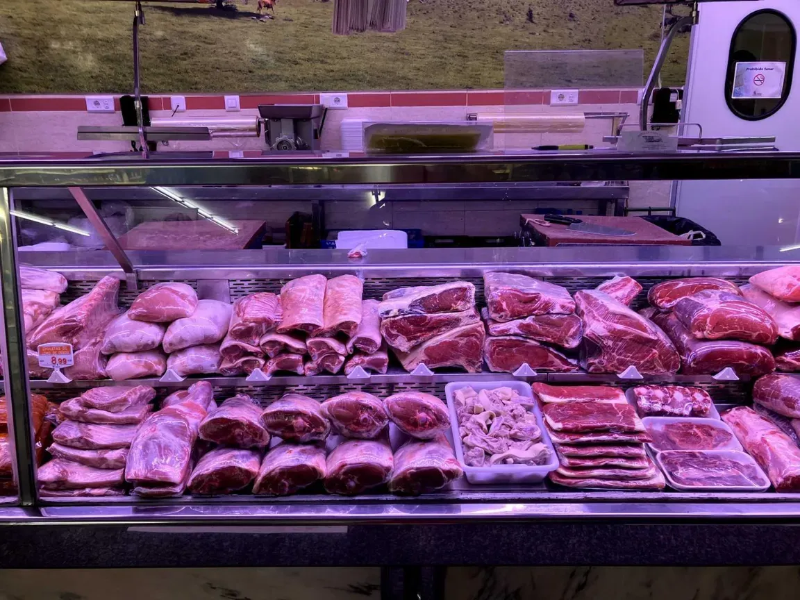 Exhibición de productos frescos en un supermercado con filas de cebollas rojas en recipientes metálicos y etiquetas de precio.