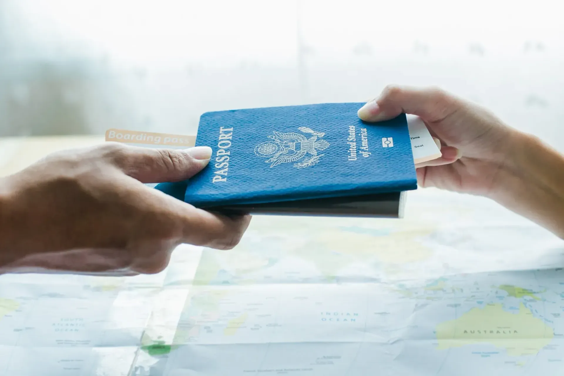 Manos intercambiando un pasaporte azul por un mapa.
