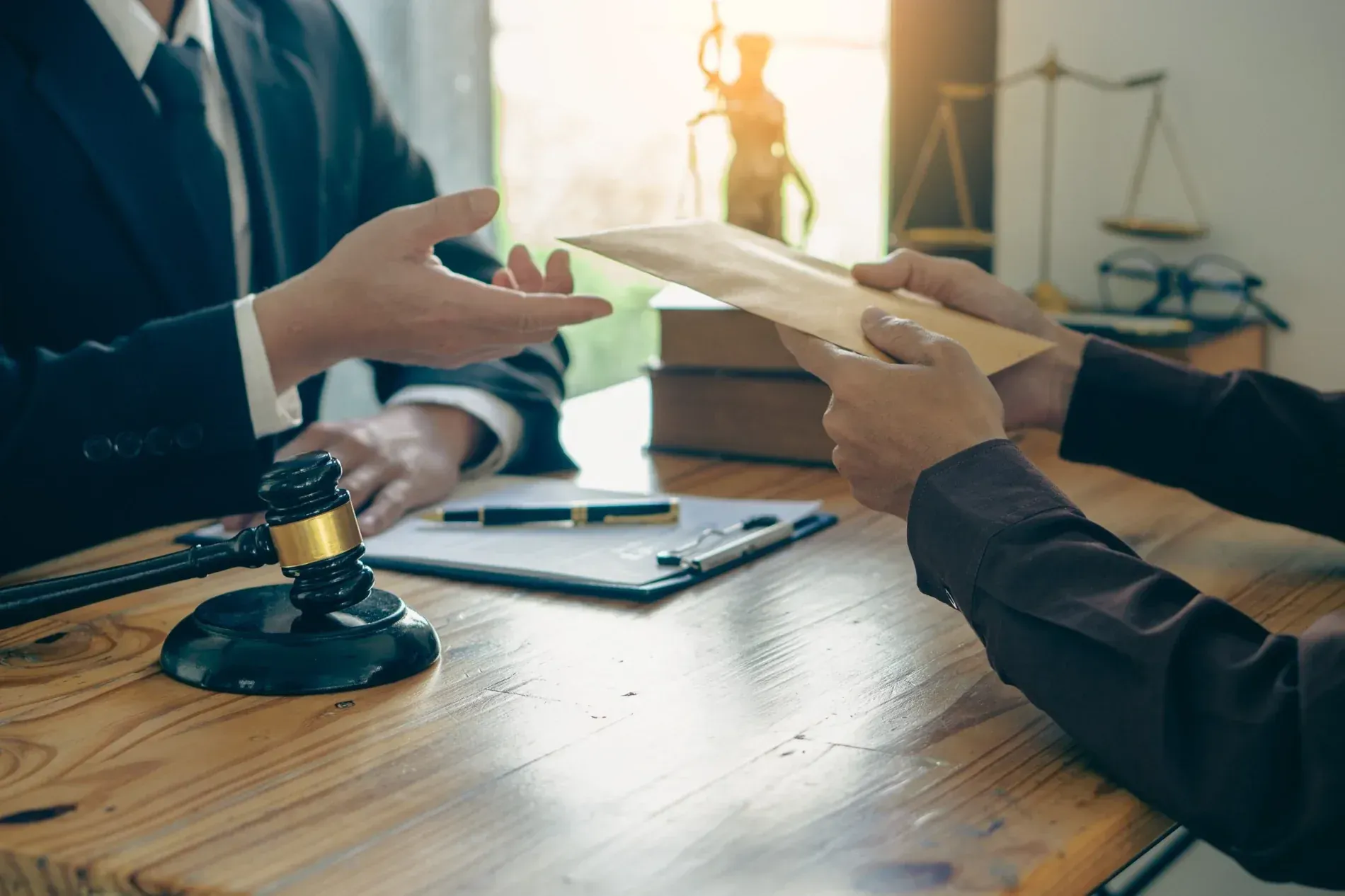 Dos personas intercambiando un documento en una oficina, con un mazo y una balanza de la justicia visibles.
