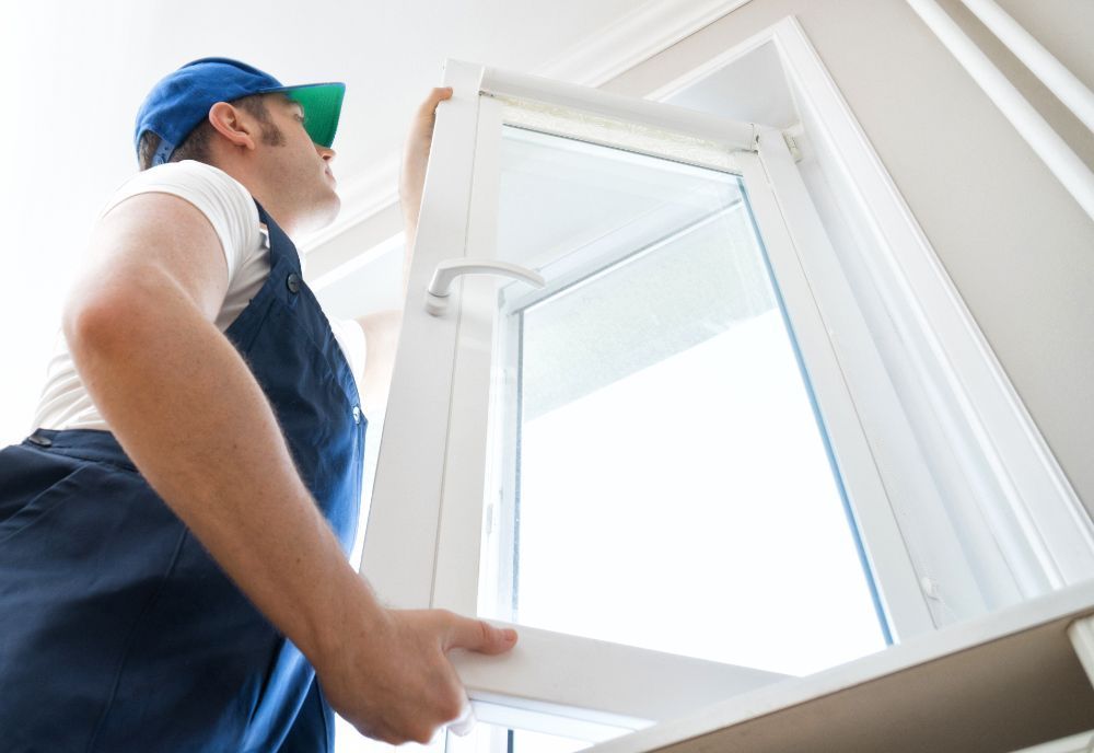 Ein Mann baut ein Fenster in einem Haus ein.