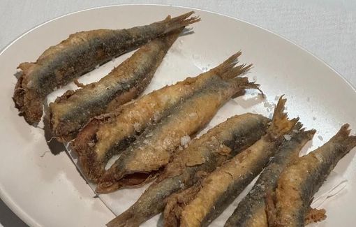 Fried anchovies on a white plate, seasoned with salt.