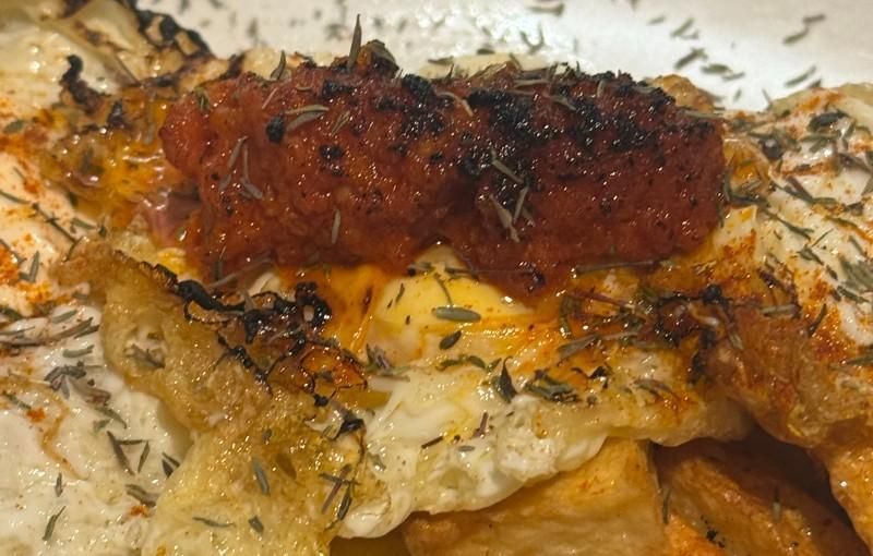 Huevos fritos con chorizo ​​y hierbas, sobre patatas crujientes.