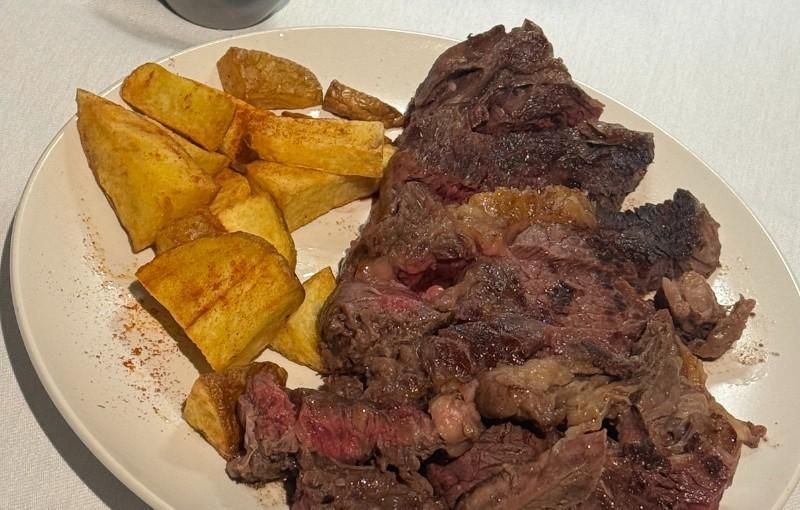 Plato de filete en rodajas con patatas fritas doradas. Se aprecia la carne roja.