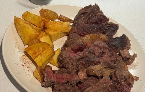 Plato de filete en rodajas con patatas fritas doradas. Se aprecia la carne roja.