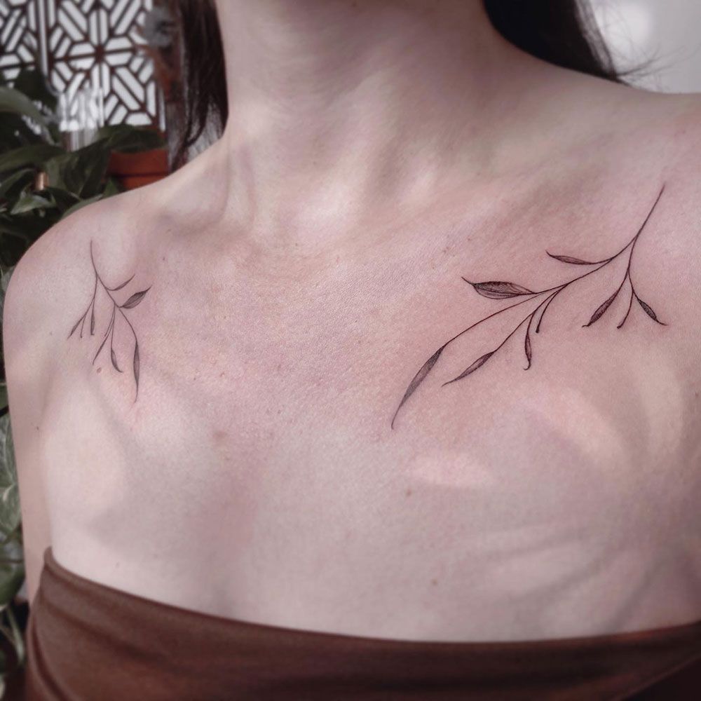 Eine Frau hat ein Tattoo mit zwei Zweigen auf ihrer Brust