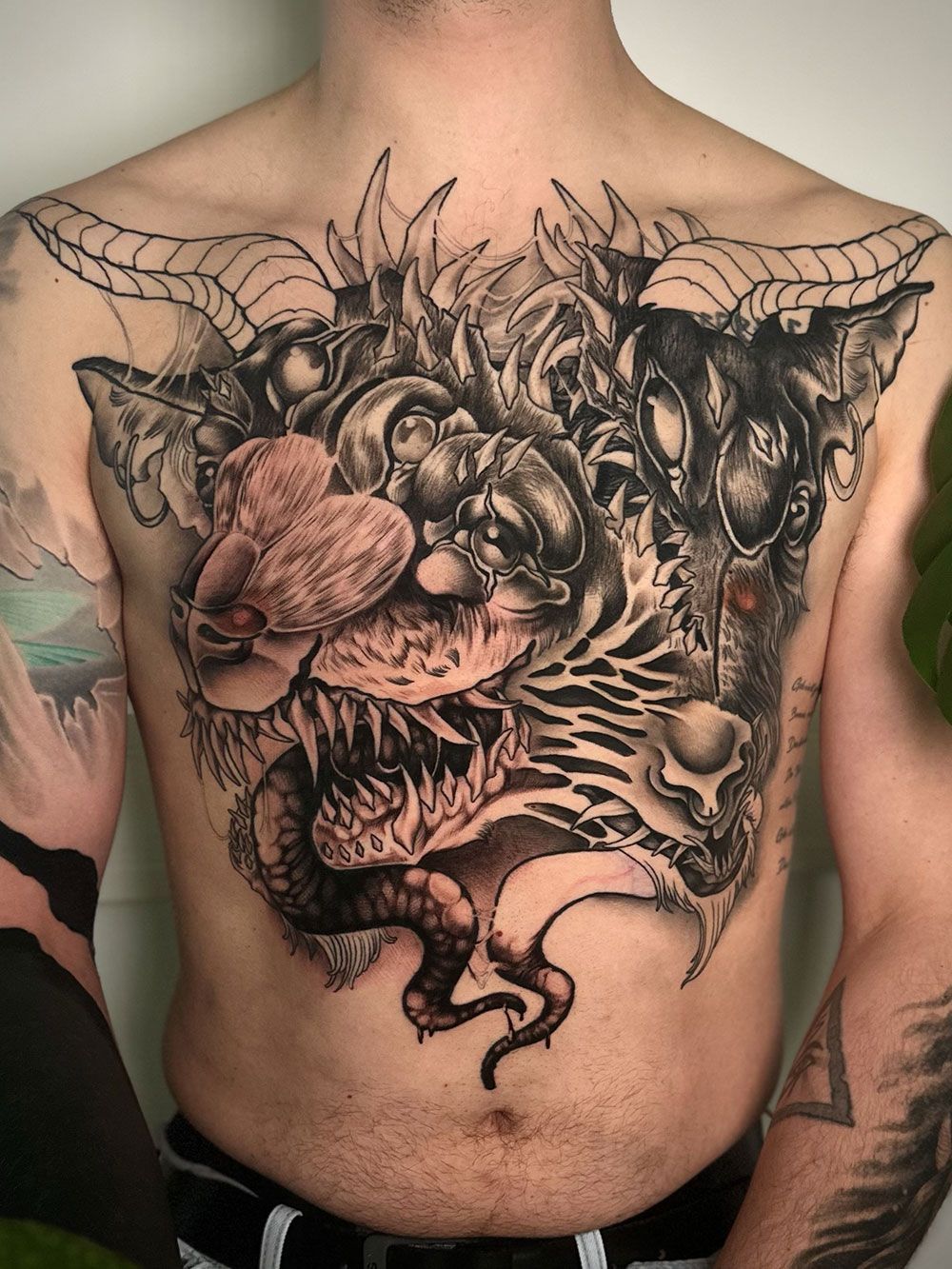 Ein Mann hat ein Monster-Tattoo auf seiner Brust.