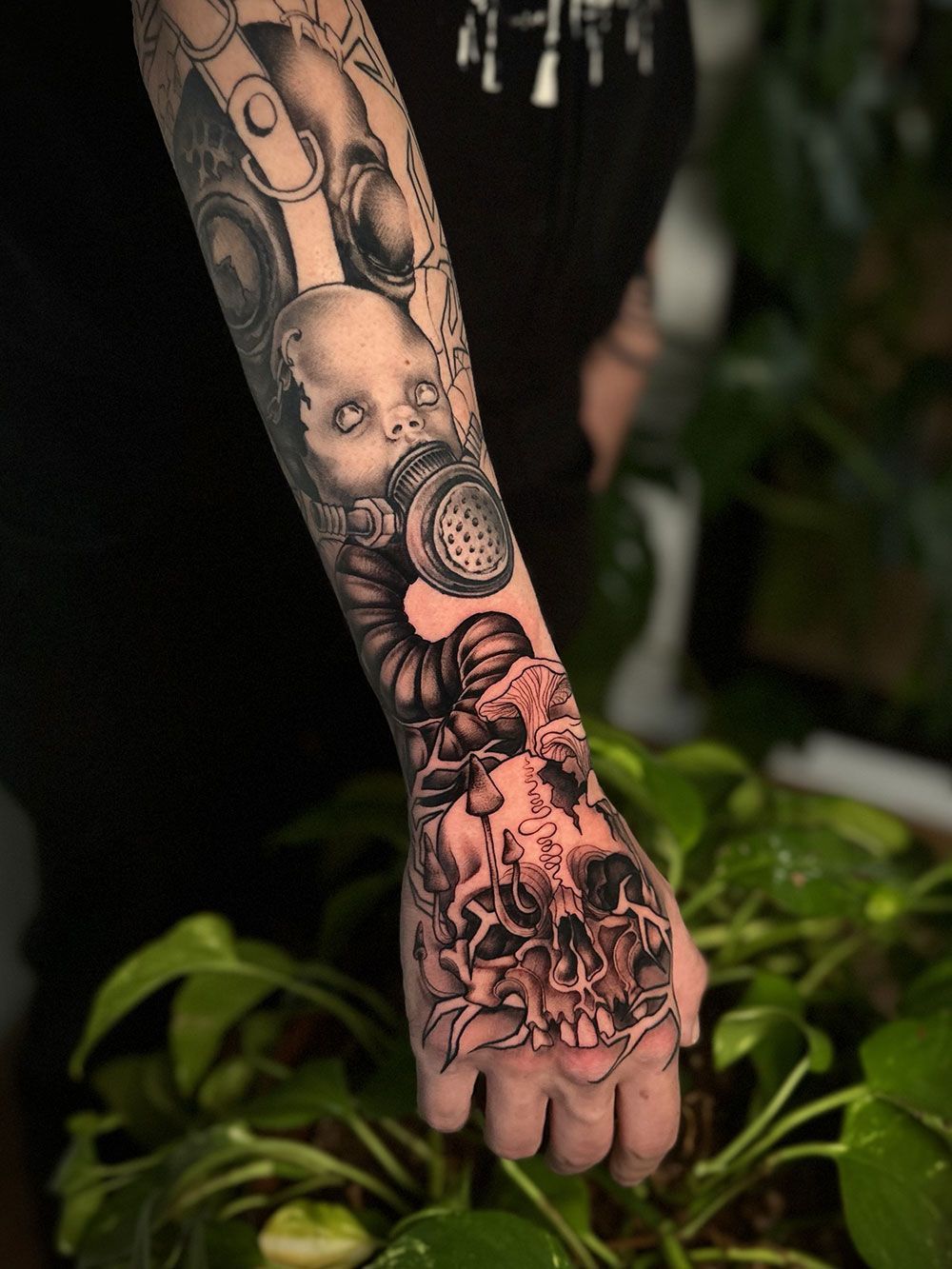 Eine Person mit der Tätowierung eines Babys mit Gasmaske auf dem Arm.