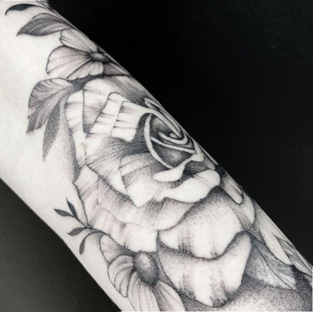 Ein schwarz-weißes Tattoo einer Rose auf dem Arm einer Person