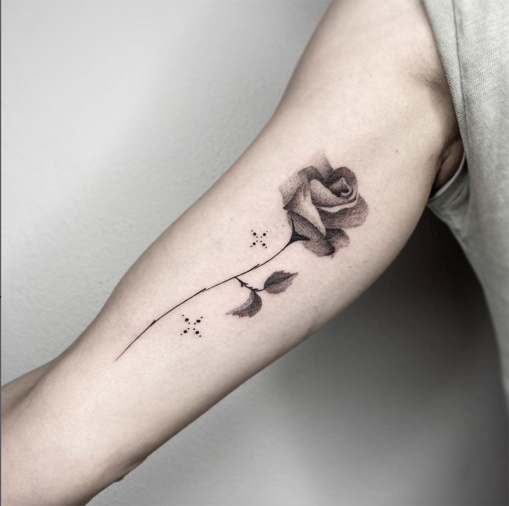 Ein schwarz-weißes Tattoo einer Rose auf dem Arm einer Person
