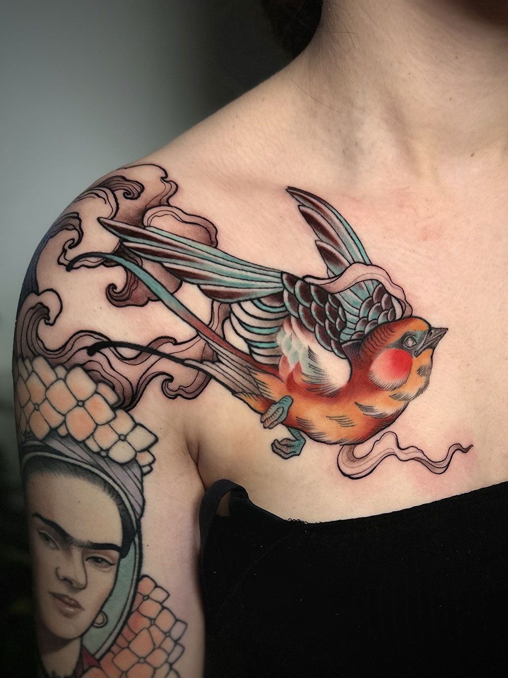 Eine Frau hat ein Vogeltattoo auf ihrer Schulter