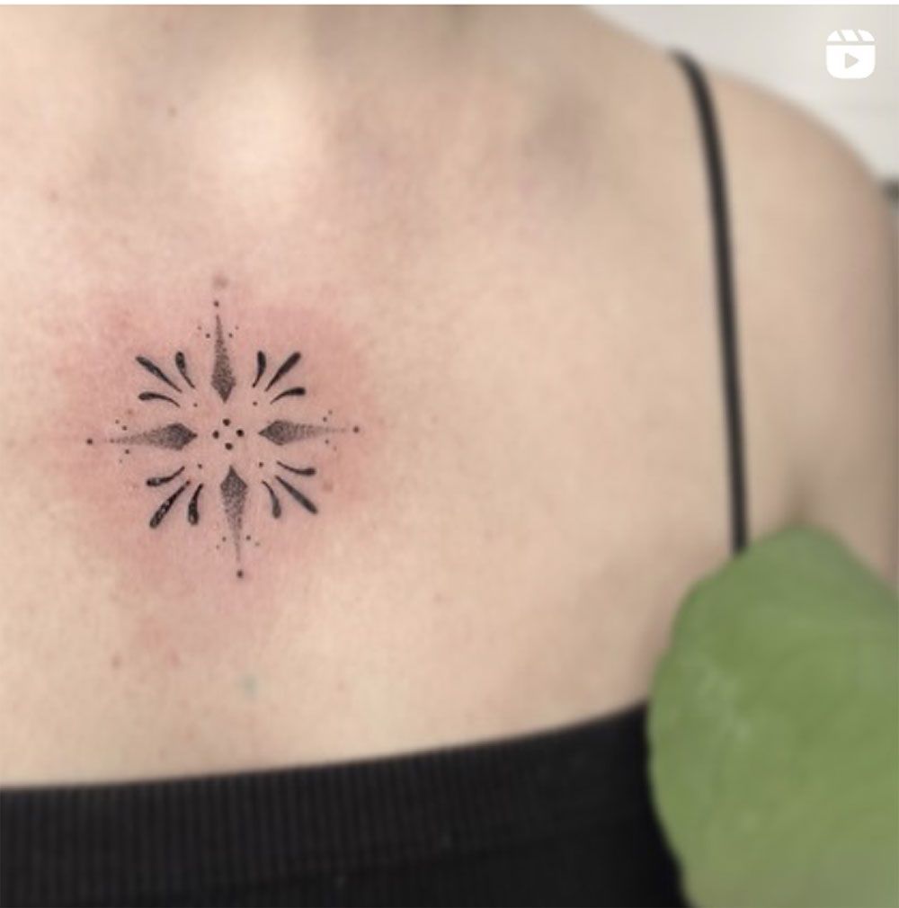 Eine Frau hat ein kleines Tattoo auf der Brust