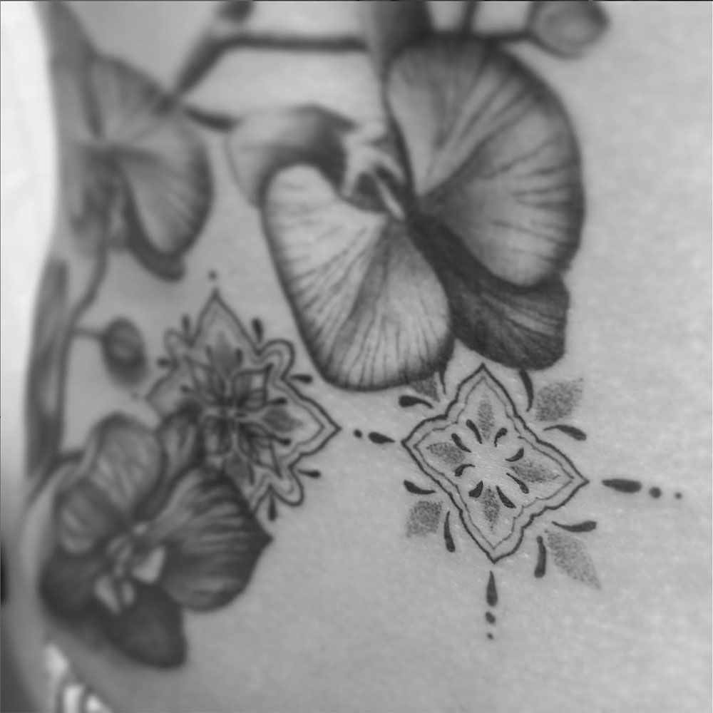 Ein Schwarzweißfoto einer Tätowierung mit Schmetterlingen und Blumen