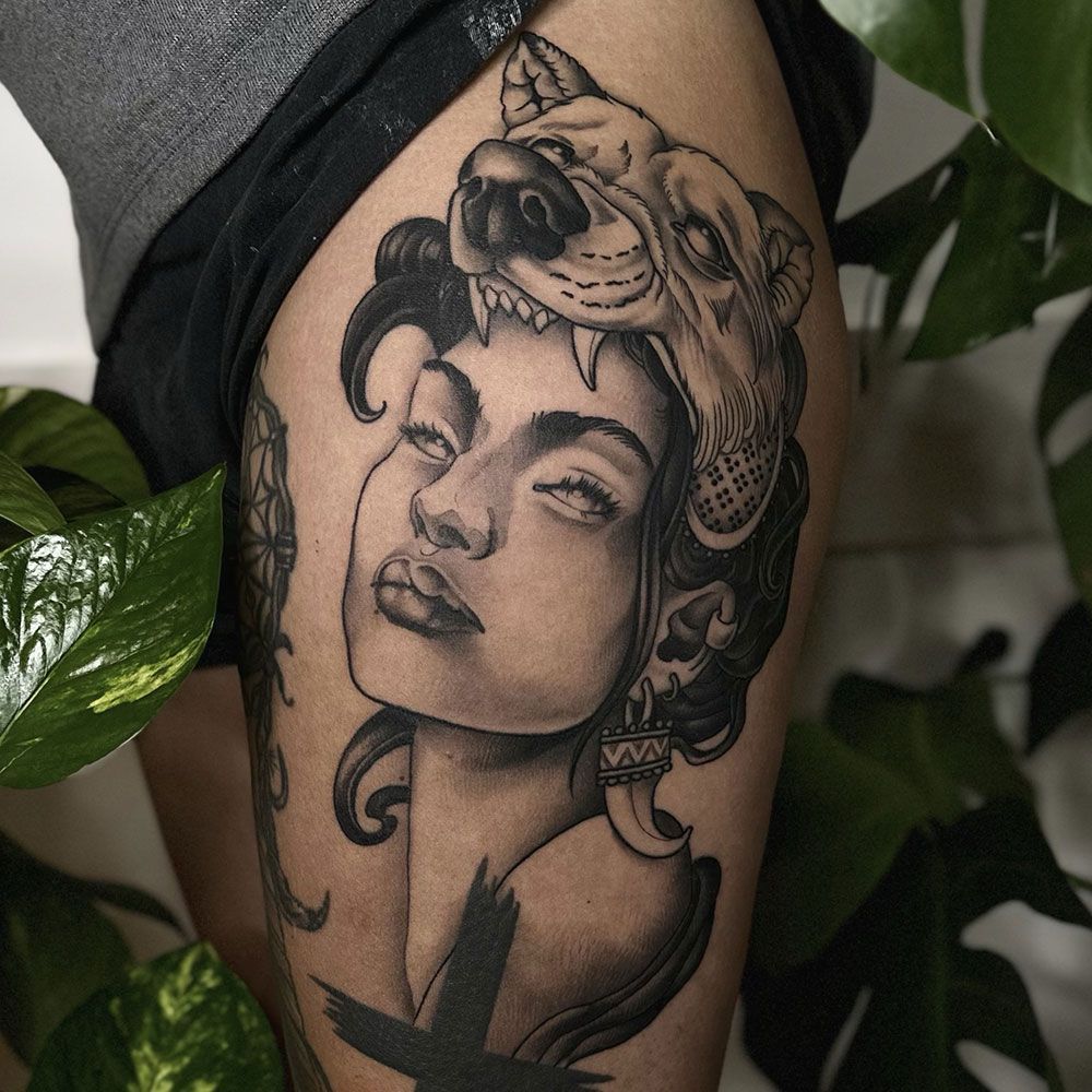 Eine Frau hat eine Tätowierung einer Frau mit einem Wolf auf dem Kopf.