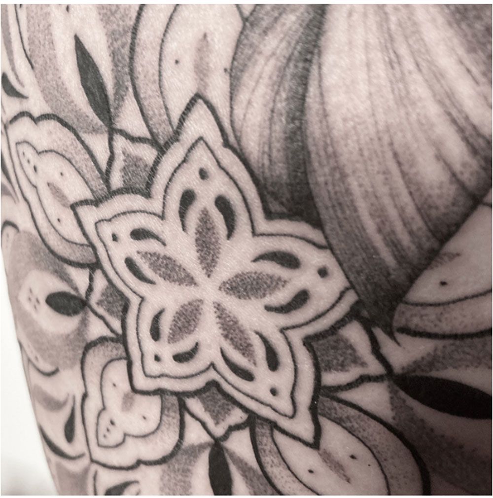 Ein schwarz-weißes Tattoo einer Blume auf dem Arm einer Person