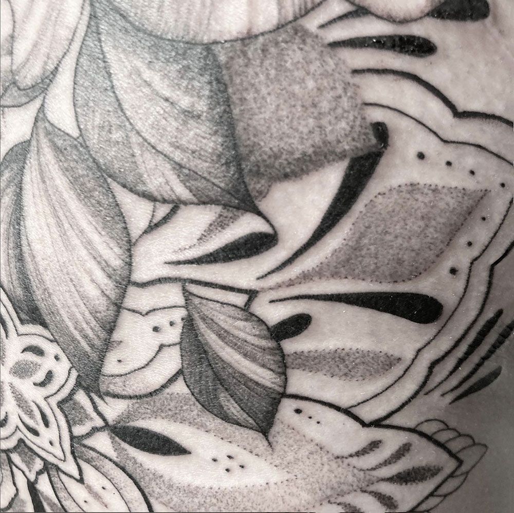 Ein schwarz-weißes Tattoo einer Blume und Blättern