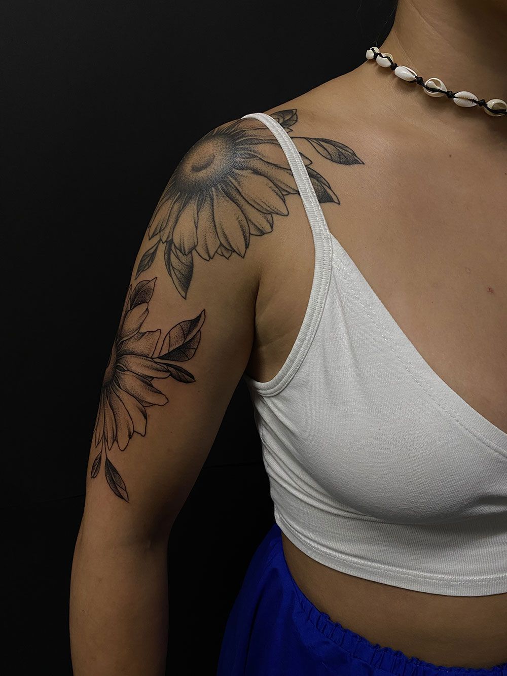 Eine Frau hat eine Sonnenblume auf ihrer Schulter tätowiert.