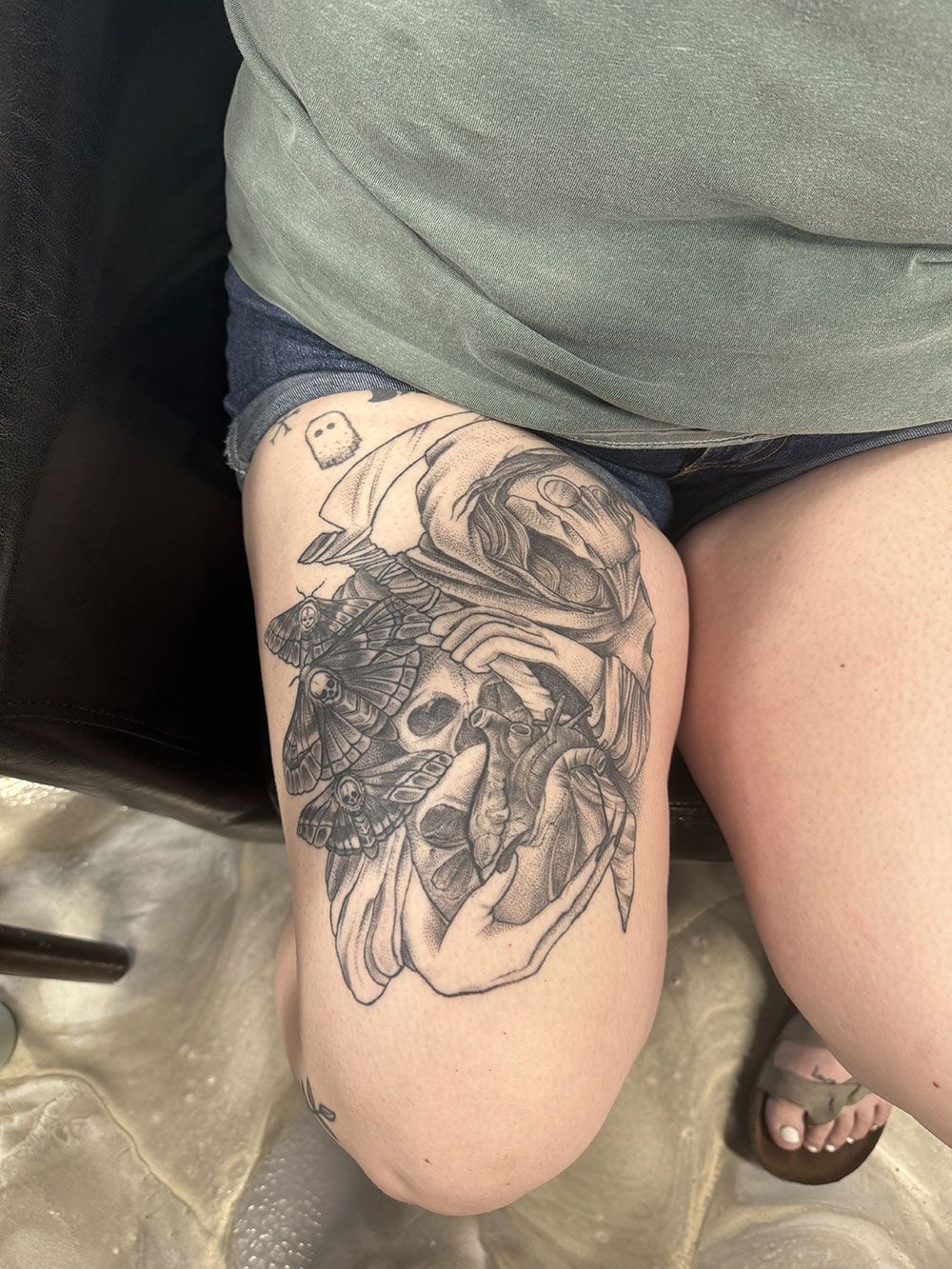 Eine Frau mit einer Tätowierung am Bein sitzt auf einem Stuhl.