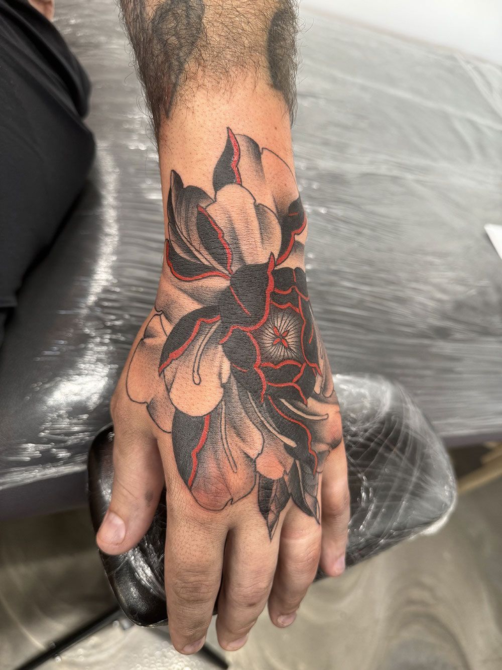Ein Mann hat eine Blumentätowierung auf seiner Hand.