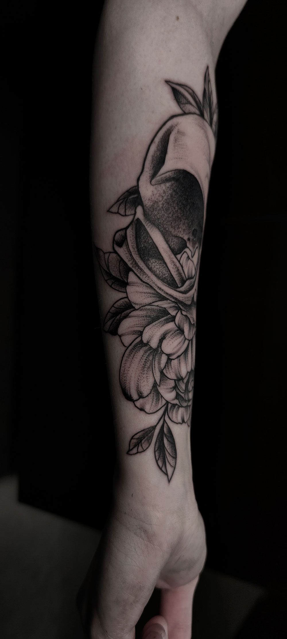 Eine Nahaufnahme des Unterarms einer Person mit einer Tätowierung eines Vogels und von Blumen.