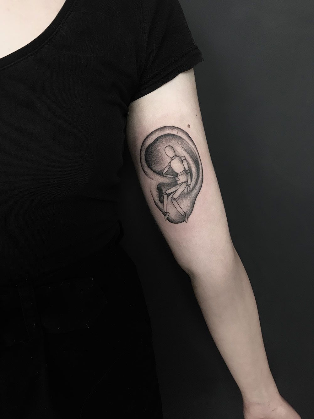 Eine Frau hat ein Tattoo mit einem Baby im Ohr ihres Arms.