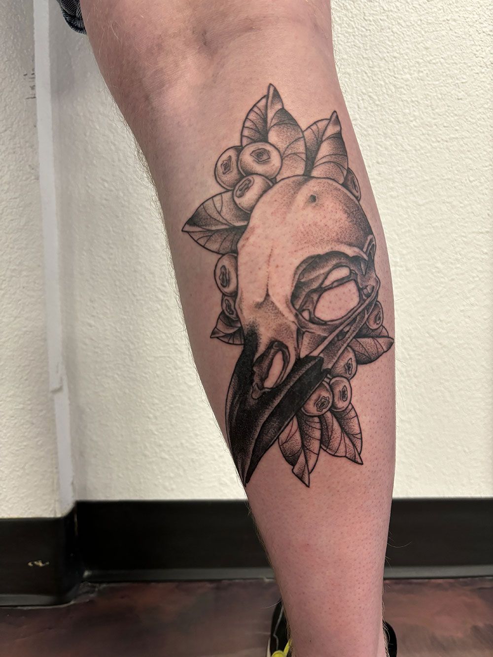 Eine Person hat eine Tätowierung eines Vogelschädels auf ihrem Bein.